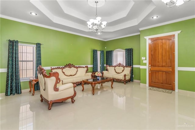 living room with a notable chandelier, ornamental molding, and a tray ceiling