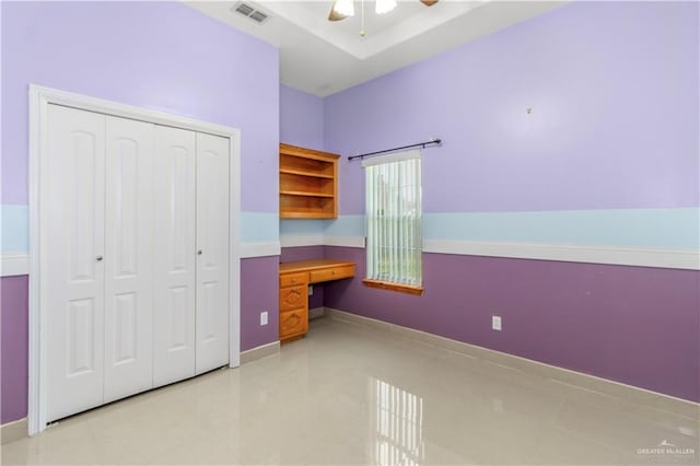 unfurnished bedroom featuring ceiling fan, built in desk, and a closet