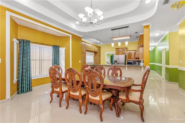 tiled dining area featuring a tray ceiling, ornamental molding, and an inviting chandelier