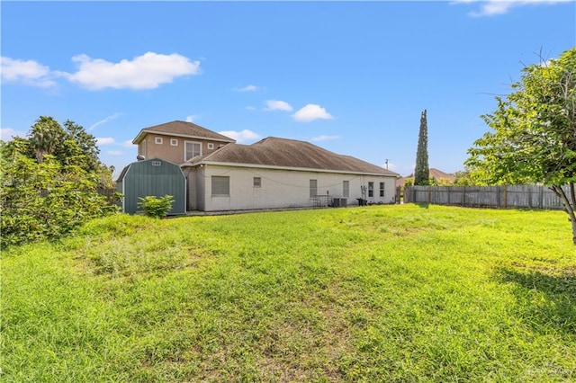 back of house with a yard and a storage shed