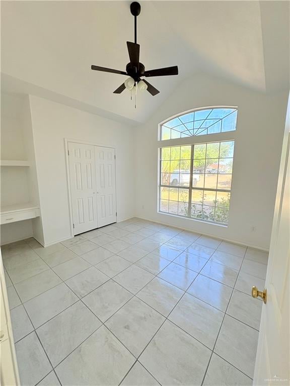 unfurnished bedroom featuring ceiling fan, a closet, light tile patterned flooring, and vaulted ceiling