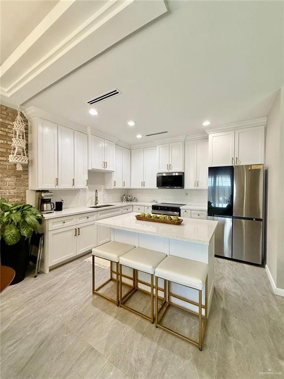 1925 Sunset Dr, Mission, TX 78572 - kitchen with appliances with stainless steel finishes, white cabinetry, a sink, light countertops, and a center island