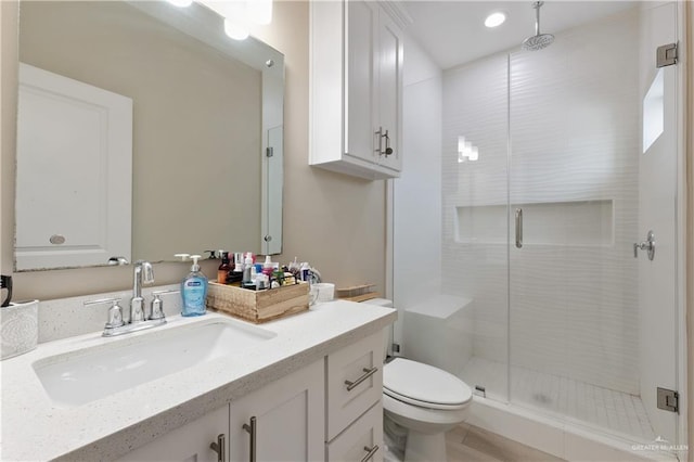 bathroom with a stall shower, toilet, and vanity