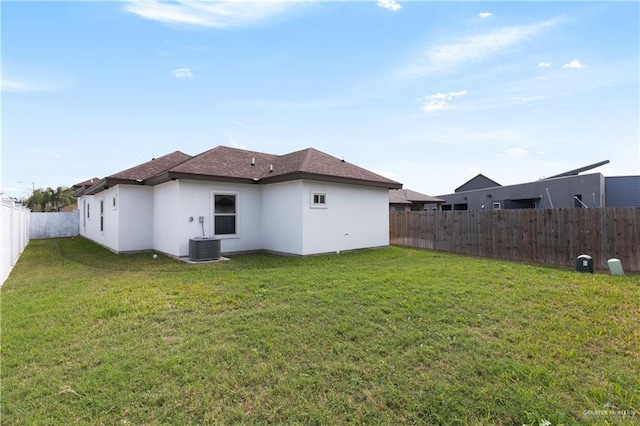 back of property with a yard, a fenced backyard, central AC, and stucco siding