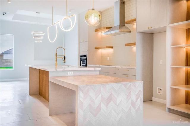 kitchen with white cabinetry, sink, an island with sink, decorative light fixtures, and island range hood