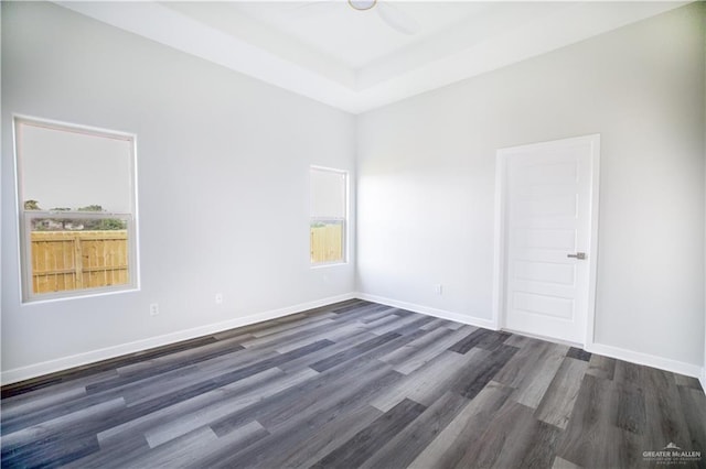 empty room with a wealth of natural light, dark wood-type flooring, and ceiling fan