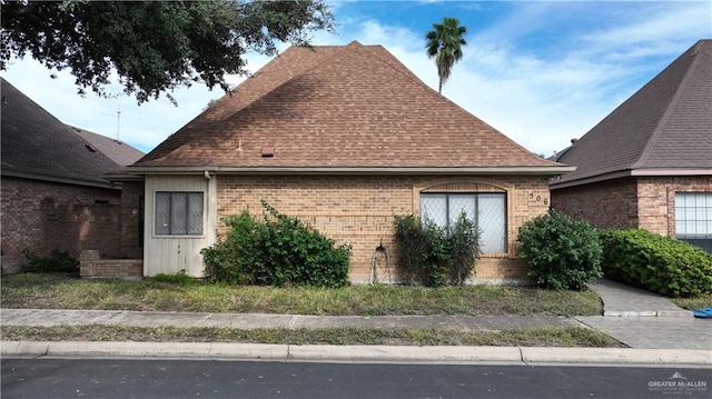 view of side of home with brick siding and a shingled roof