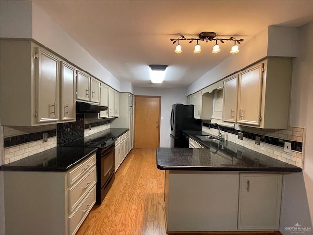 kitchen featuring sink, black appliances, decorative backsplash, kitchen peninsula, and light wood-type flooring