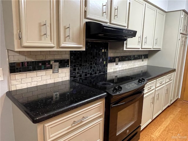 kitchen with black electric range oven, light hardwood / wood-style floors, and decorative backsplash