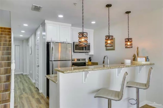 200 Padre Blvd Unit 2102, South Padre Island, TX 78597 - kitchen featuring light wood-type flooring, visible vents, a breakfast bar, stainless steel appliances, and white cabinets