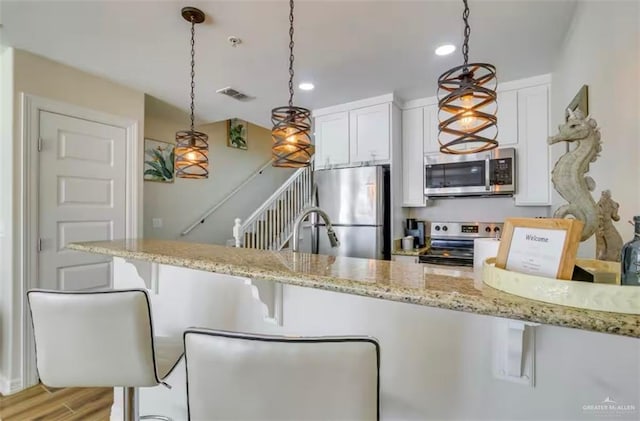 200 Padre Blvd Unit 2102, South Padre Island, TX 78597 - kitchen with white cabinetry, hanging light fixtures, light wood finished floors, and stainless steel appliances