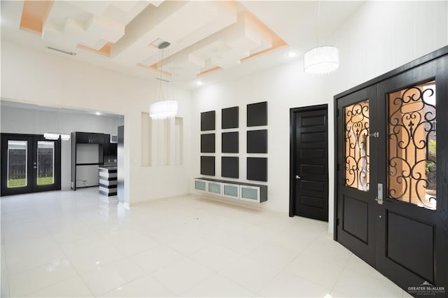 tiled entrance foyer featuring a raised ceiling, a high ceiling, and french doors