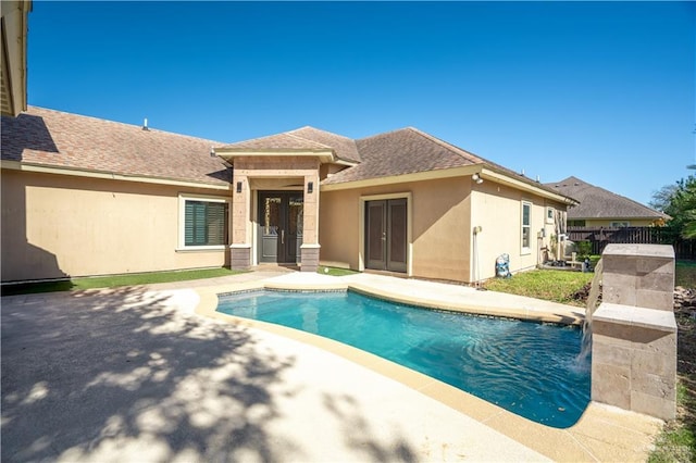 view of pool with pool water feature, a patio, and french doors