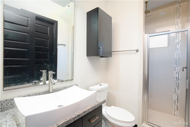 bathroom with vanity, toilet, and a shower with shower door