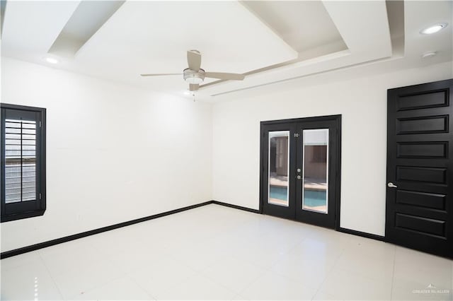 empty room with french doors, a raised ceiling, and ceiling fan