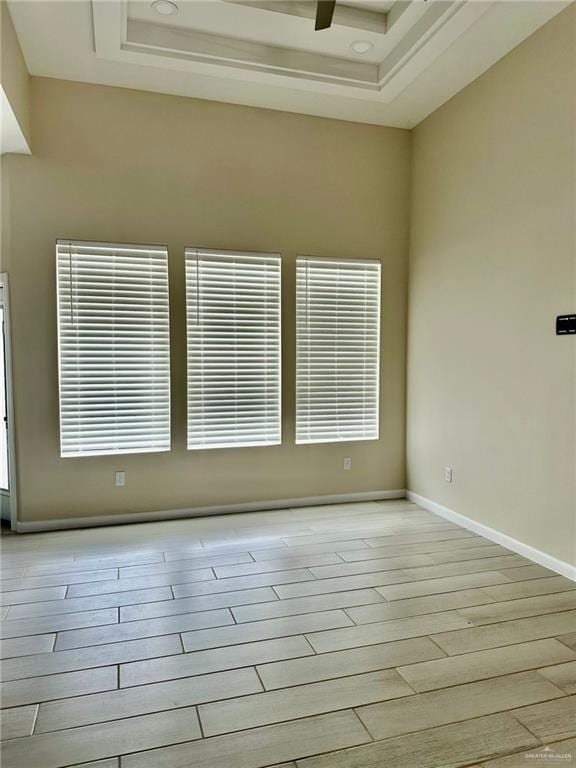 empty room with a tray ceiling and light wood-type flooring