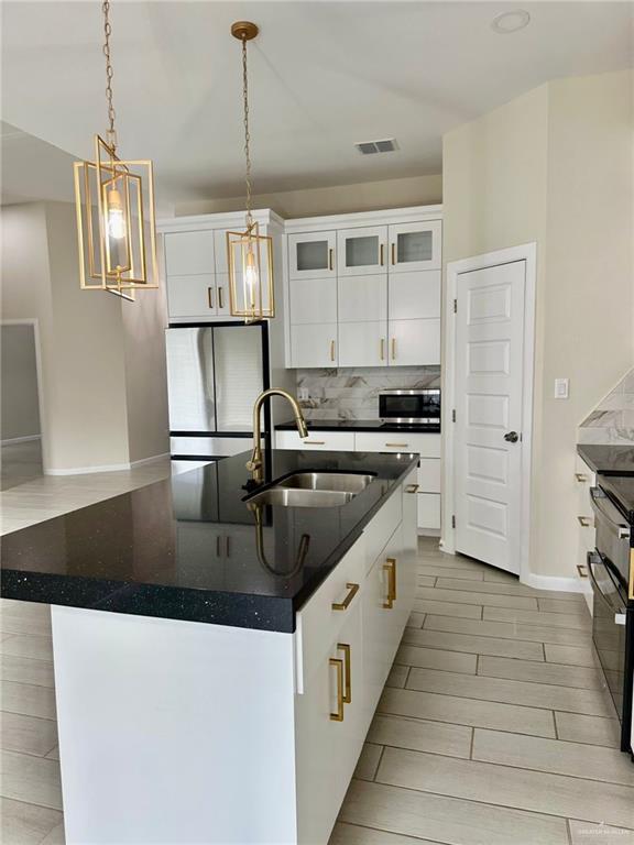 kitchen featuring a center island with sink, white cabinetry, sink, and appliances with stainless steel finishes