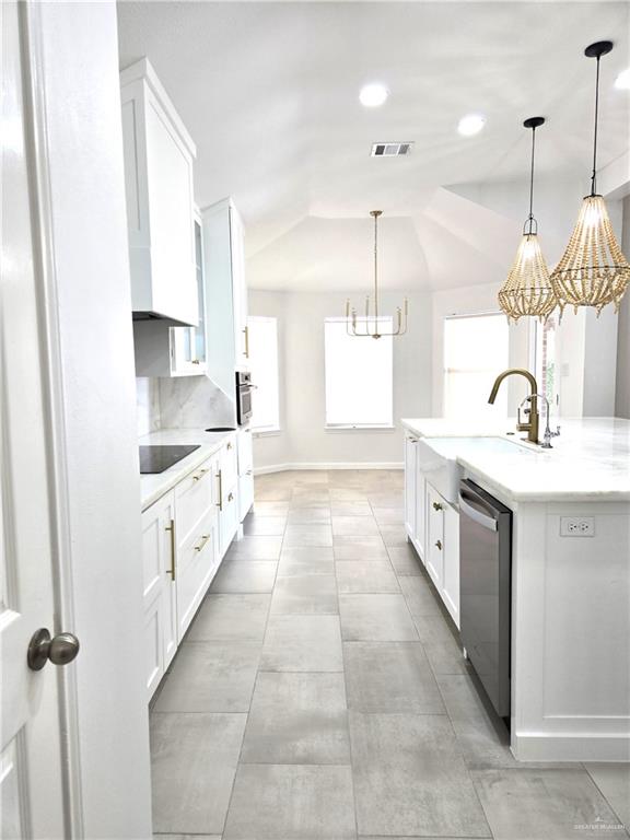 kitchen with white cabinets, sink, hanging light fixtures, vaulted ceiling, and appliances with stainless steel finishes