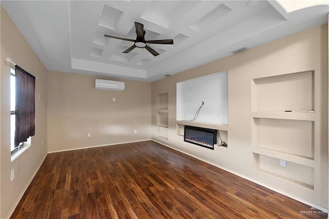 unfurnished living room featuring visible vents, built in features, coffered ceiling, a glass covered fireplace, and an AC wall unit