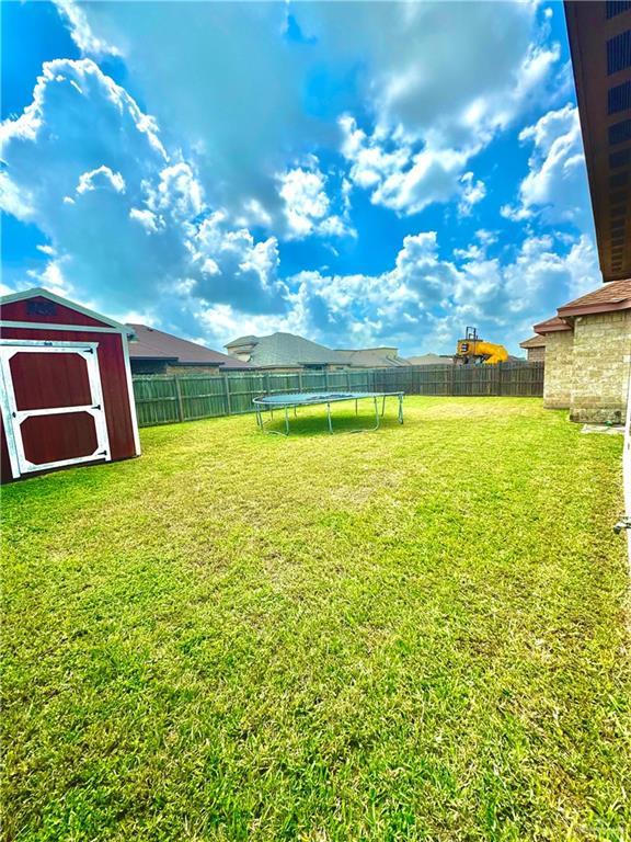 view of yard featuring a trampoline and a storage shed