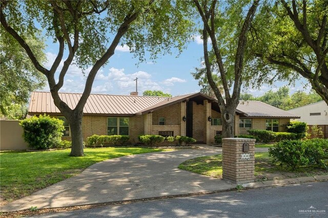 106 E Ithaca Ave, Mcallen, TX 78501 - view of front of property featuring a standing seam roof, brick siding, a front yard, a chimney, and metal roof