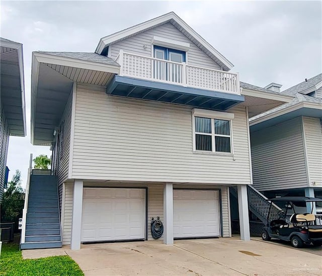 view of front of home with a balcony, driveway, an attached garage, and stairs