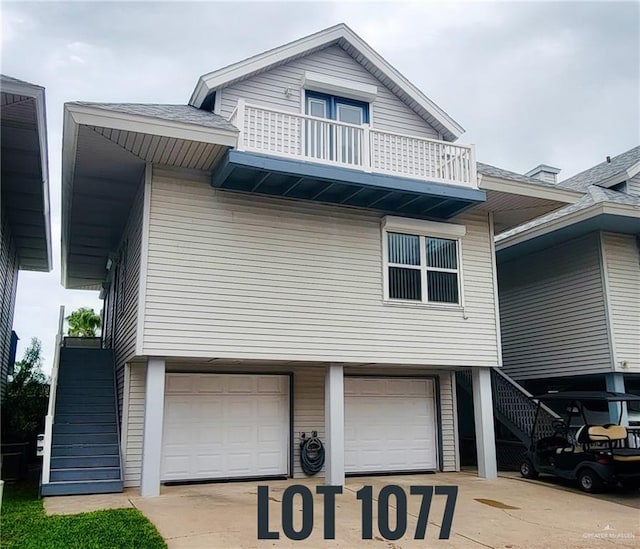 view of front of house with driveway, stairway, an attached garage, and a balcony