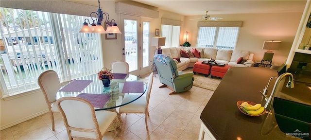 dining area with light tile patterned flooring, plenty of natural light, and ceiling fan with notable chandelier