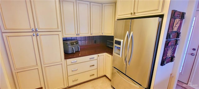 kitchen with dark countertops, cream cabinets, and stainless steel fridge with ice dispenser