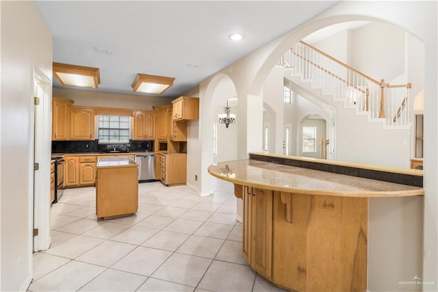 1711 Solar Dr, Mission, TX 78574 - kitchen with stainless steel dishwasher, a peninsula, light tile patterned floors, arched walkways, and a kitchen island