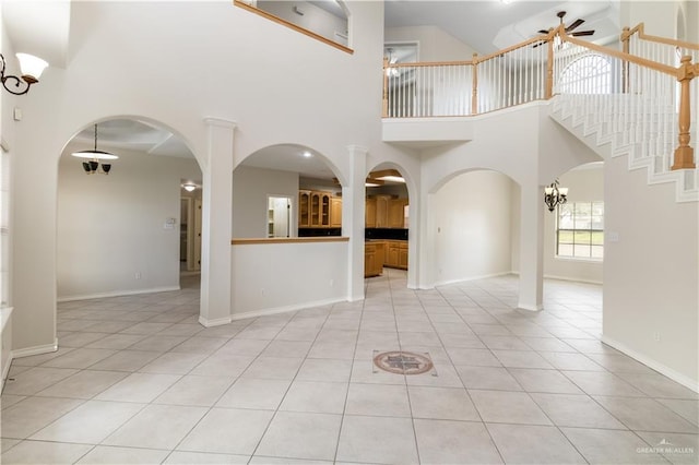 1711 Solar Dr, Mission, TX 78574 - unfurnished living room featuring ceiling fan, a high ceiling, light tile patterned flooring, baseboards, and arched walkways