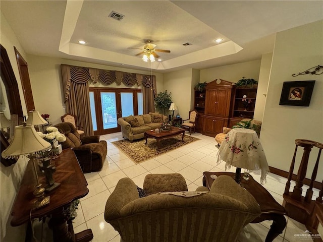 tiled living room featuring french doors, ceiling fan, and a raised ceiling