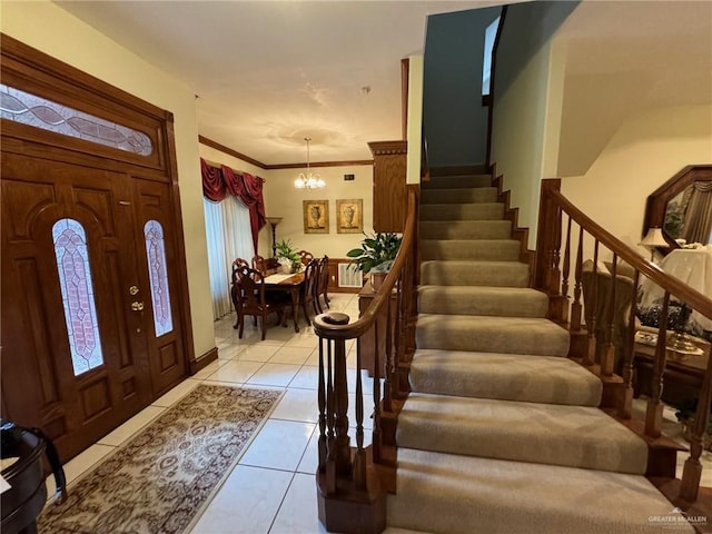 entryway with an inviting chandelier, light tile patterned floors, and crown molding