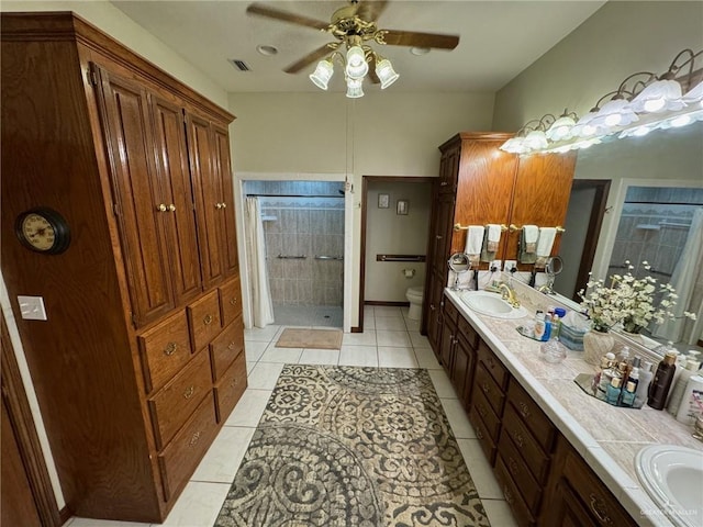 bathroom with ceiling fan, a shower with shower curtain, vanity, tile patterned floors, and toilet