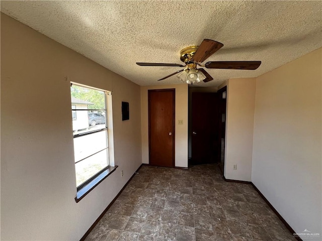 empty room featuring ceiling fan and a textured ceiling