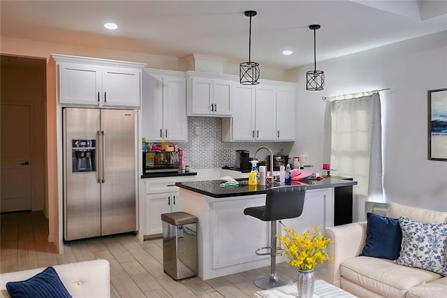 kitchen featuring white cabinetry, a center island with sink, and stainless steel fridge