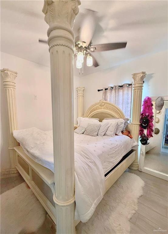 bedroom featuring light hardwood / wood-style floors, decorative columns, and ceiling fan