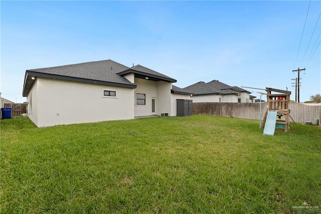 rear view of house with a playground and a yard