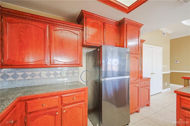 kitchen featuring light tile patterned floors, stainless steel refrigerator, and decorative backsplash