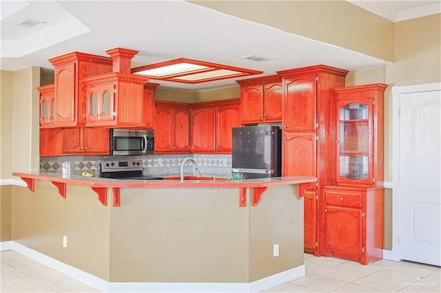 kitchen featuring sink, light tile patterned floors, a kitchen breakfast bar, stainless steel appliances, and decorative backsplash