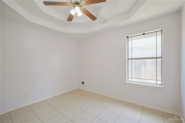 tiled spare room with ceiling fan and a raised ceiling