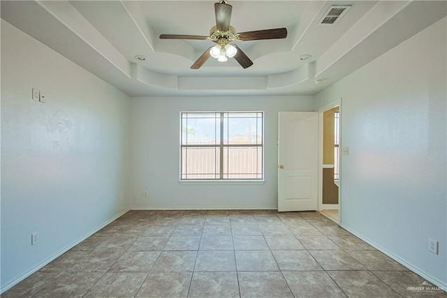 spare room with light tile patterned floors, a tray ceiling, and ceiling fan