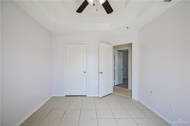 unfurnished bedroom featuring a raised ceiling, light tile patterned flooring, and ceiling fan