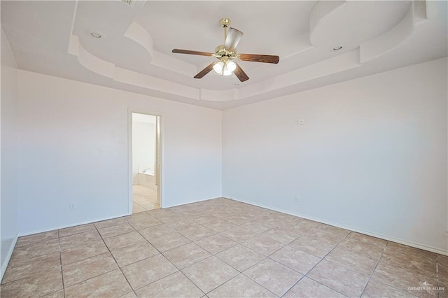 tiled empty room with a tray ceiling and ceiling fan