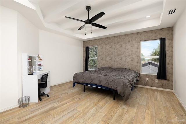 bedroom featuring a raised ceiling, ceiling fan, and light hardwood / wood-style floors