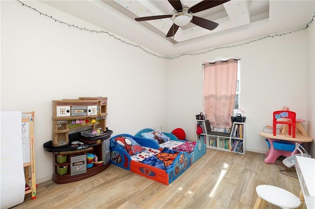 bedroom with ceiling fan, a tray ceiling, and hardwood / wood-style flooring