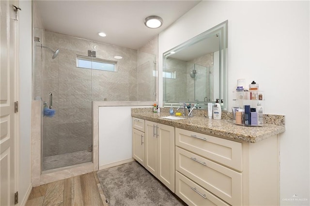 bathroom with hardwood / wood-style flooring, a shower with door, and vanity