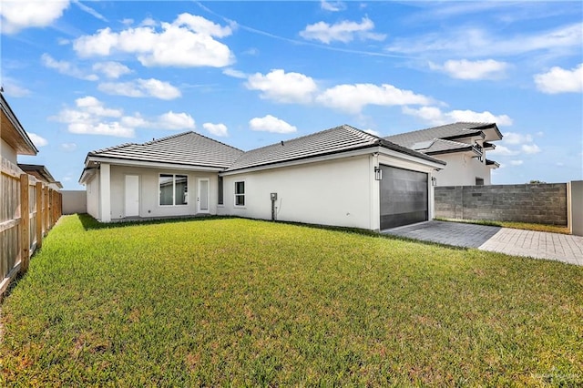 back of property with a lawn and a garage