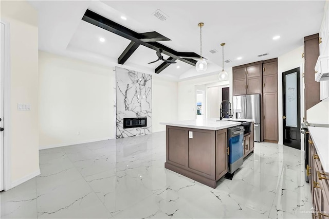 kitchen with hanging light fixtures, a premium fireplace, an island with sink, appliances with stainless steel finishes, and heating unit