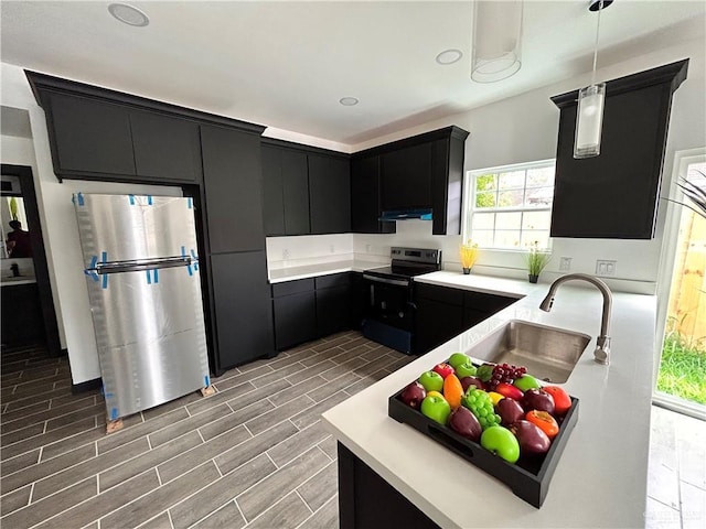 kitchen with dark cabinetry, freestanding refrigerator, a sink, electric stove, and under cabinet range hood